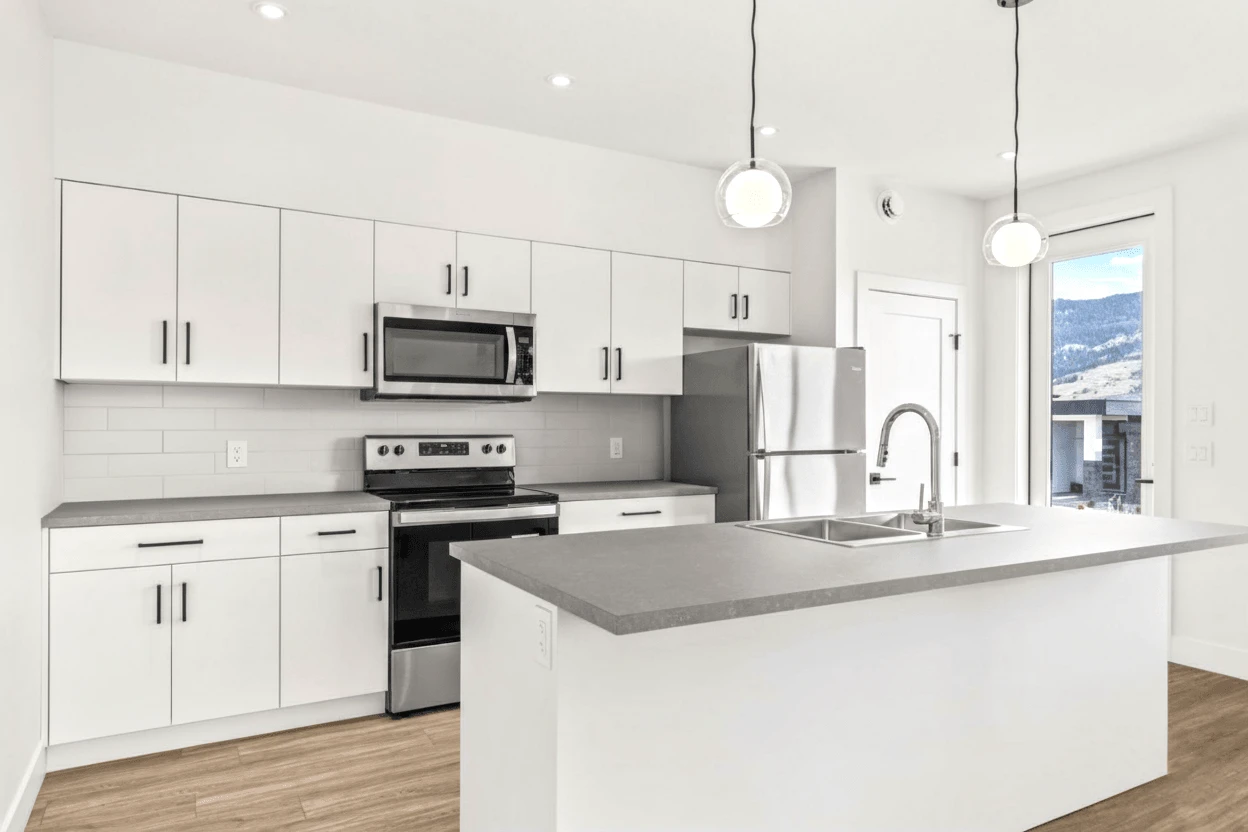 Stellar Craft Cabinetry Inc. modern white kitchen with custom cabinets, countertop, and stainless appliances