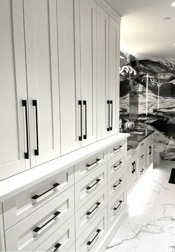 Stellar Craft Cabinetry Inc. modern white bathroom cabinetry with black hardware and marble countertops