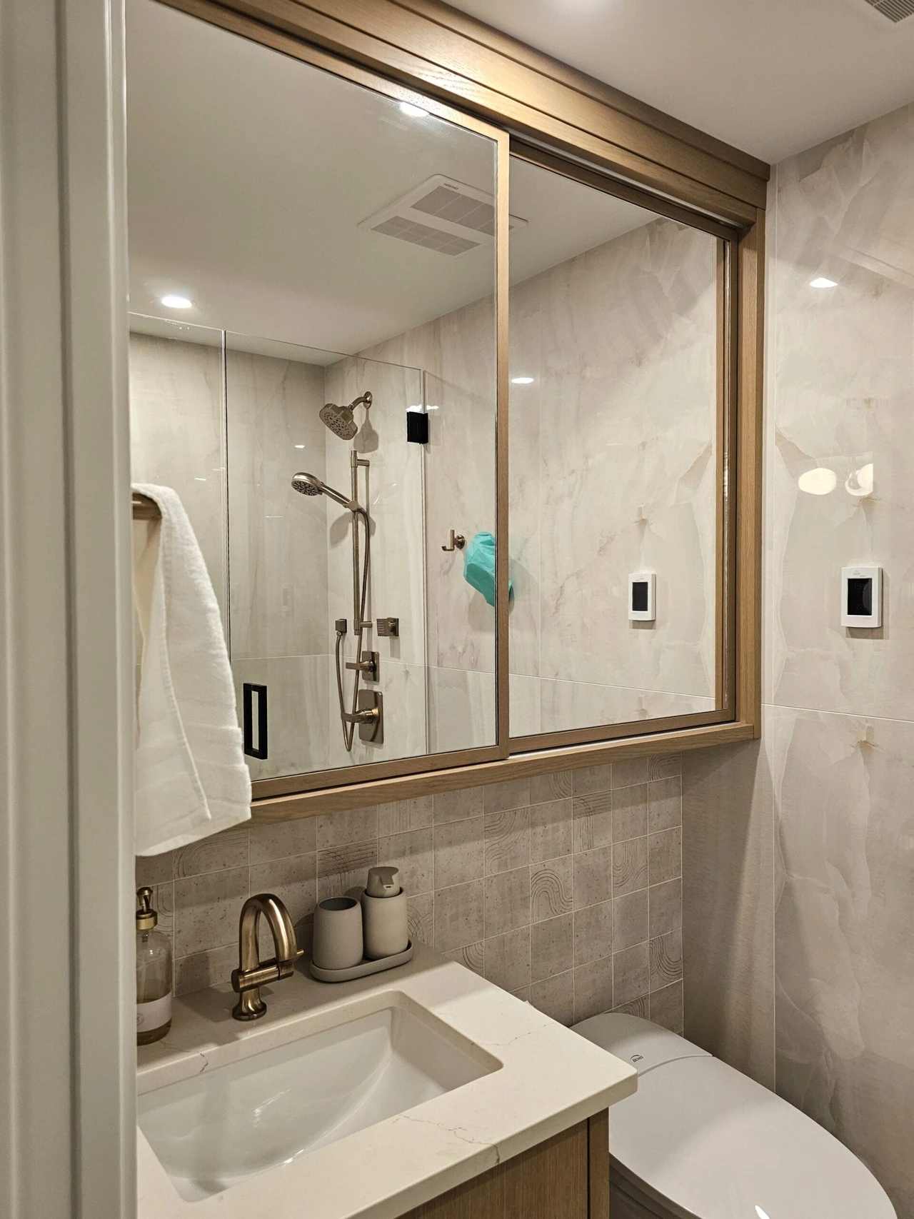 Stellar Craft Cabinetry Inc. bathroom vanity with frameless glass shower enclosure and double-sink countertop