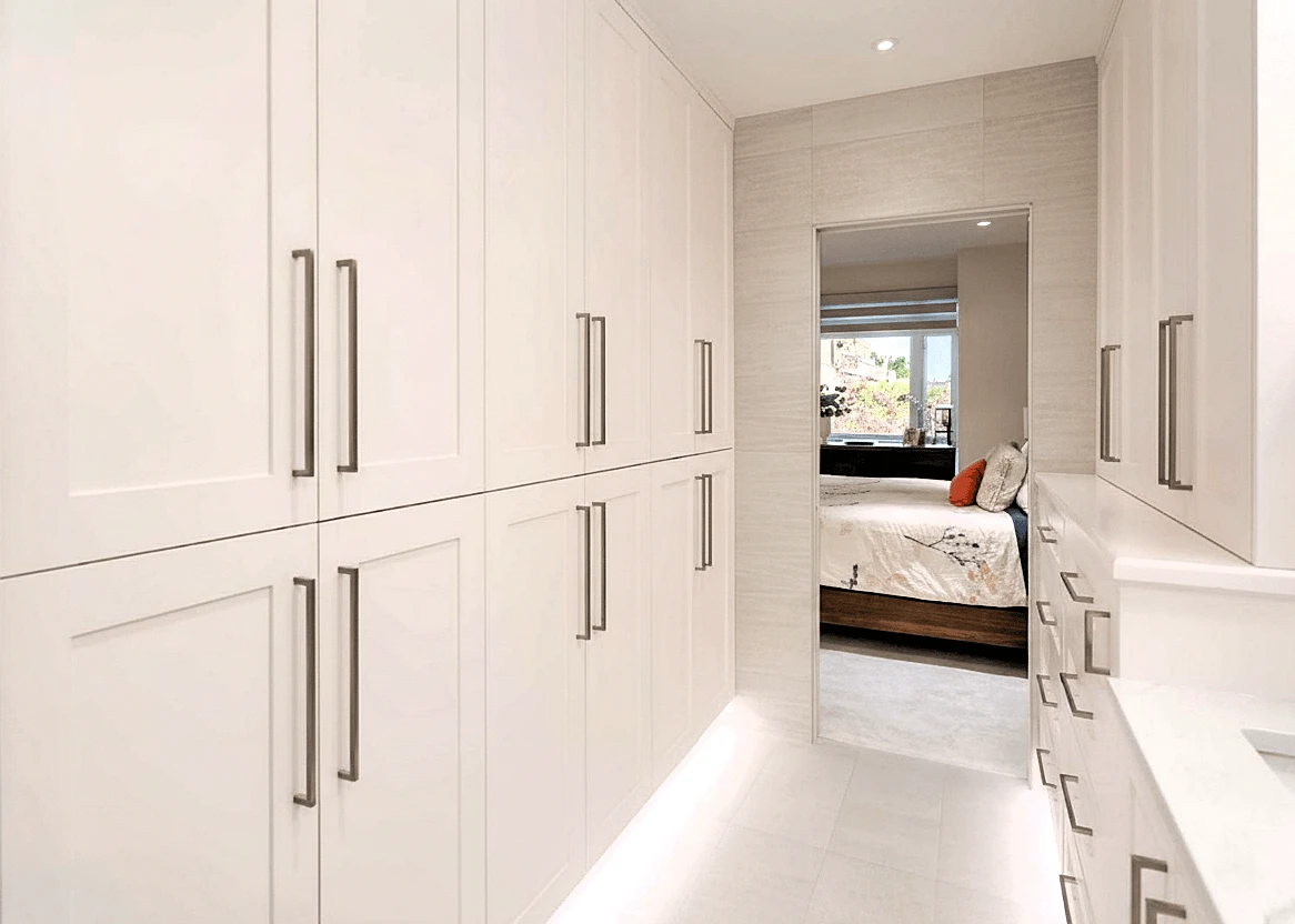 Stellar Craft Cabinetry Inc. custom white kitchen cabinetry with dark hardware and built-in storage bench