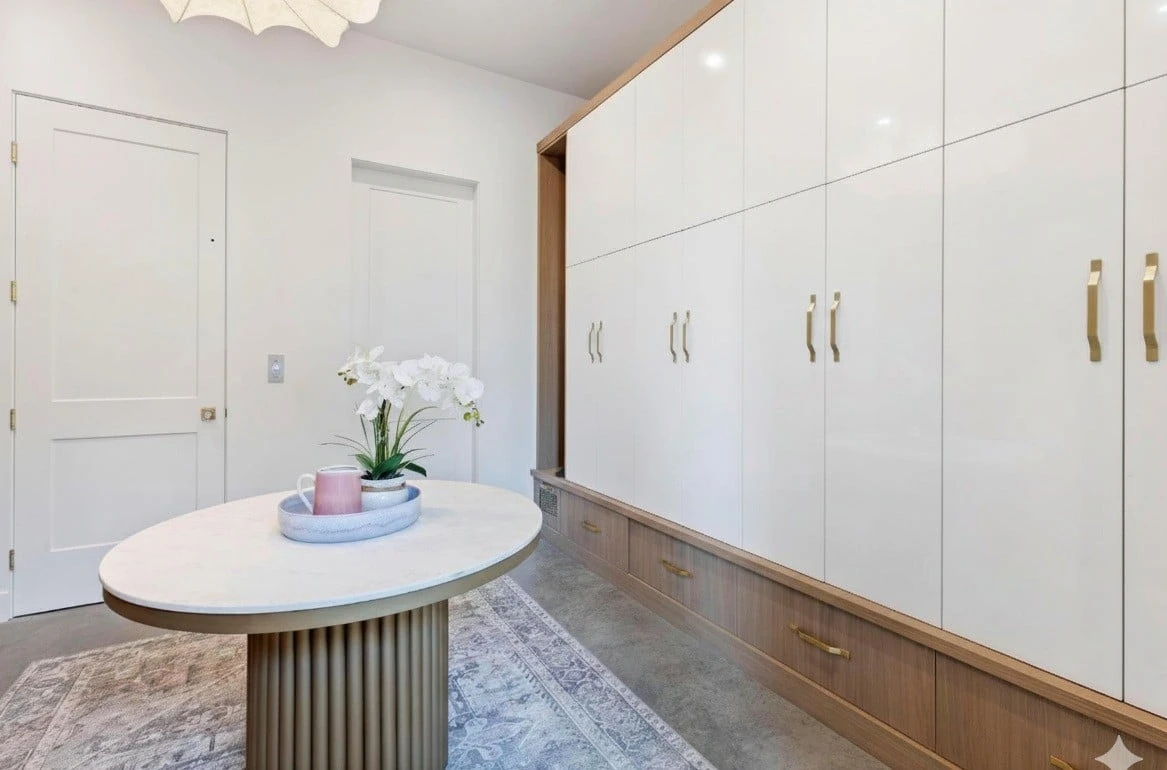 Stellar Craft Cabinetry Inc. custom white built-in cabinetry with wood base and gold hardware in a modern kitchen