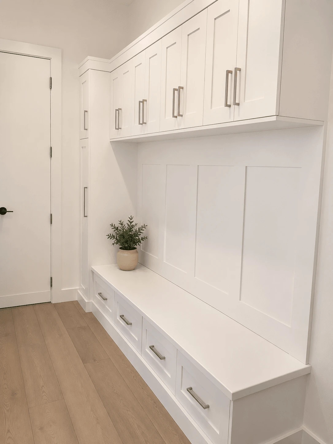 Stellar Craft Cabinetry Inc. custom white shaker cabinetry with built-in bench and decorative plant