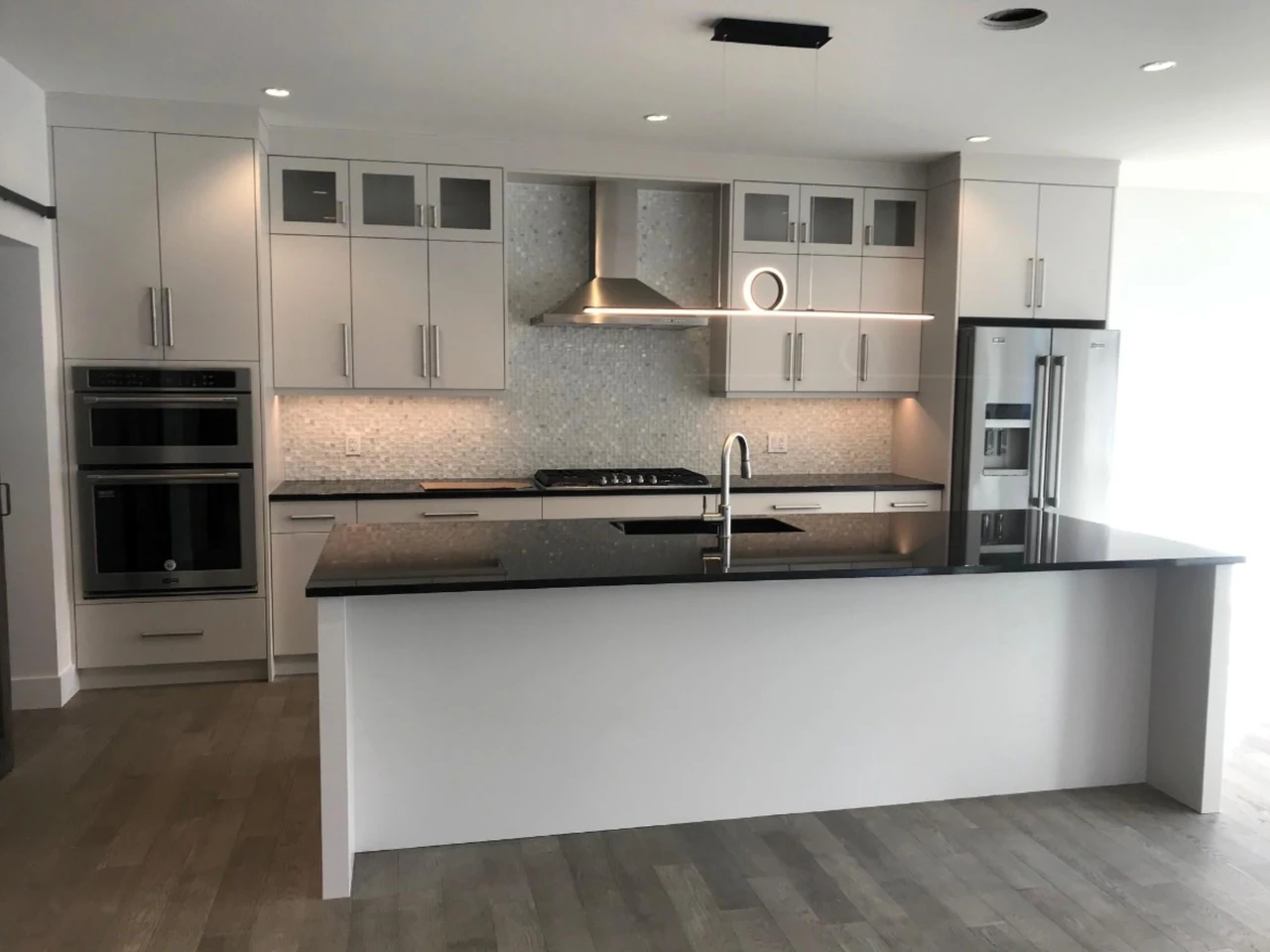 Stellar Craft Cabinetry Inc. modern white kitchen with custom cabinetry, backsplash tile, and island