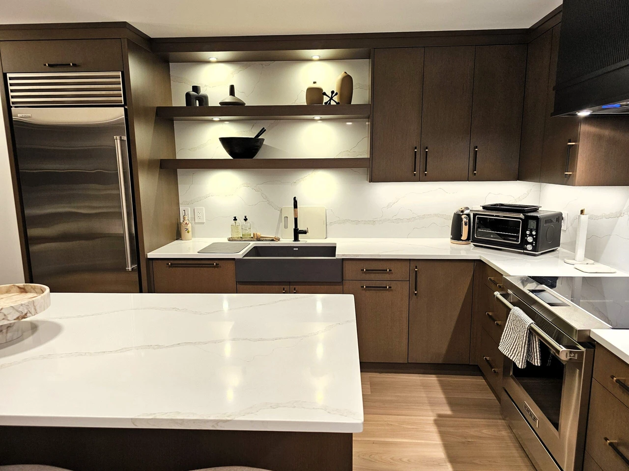 Stellar Craft Cabinetry Inc. modern kitchen with dark wood cabinetry, built-in shelving, and marble countertops