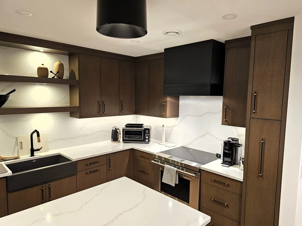 Stellar Craft Cabinetry Inc. modern L-shaped kitchen with dark wood cabinetry, waterfall quartz countertops, and under-cabinet lighting