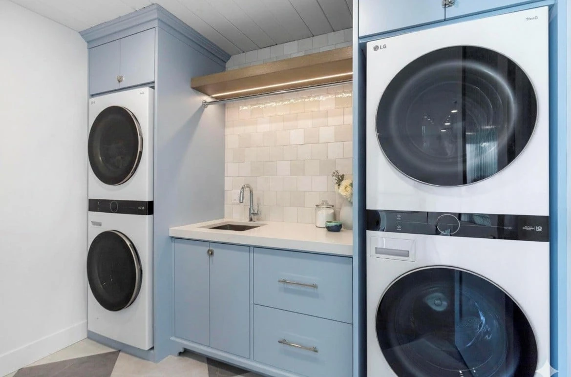 Stellar Craft Cabinetry Inc. laundry room featuring custom blue cabinetry with built-in sink and integrated washer and dryer units