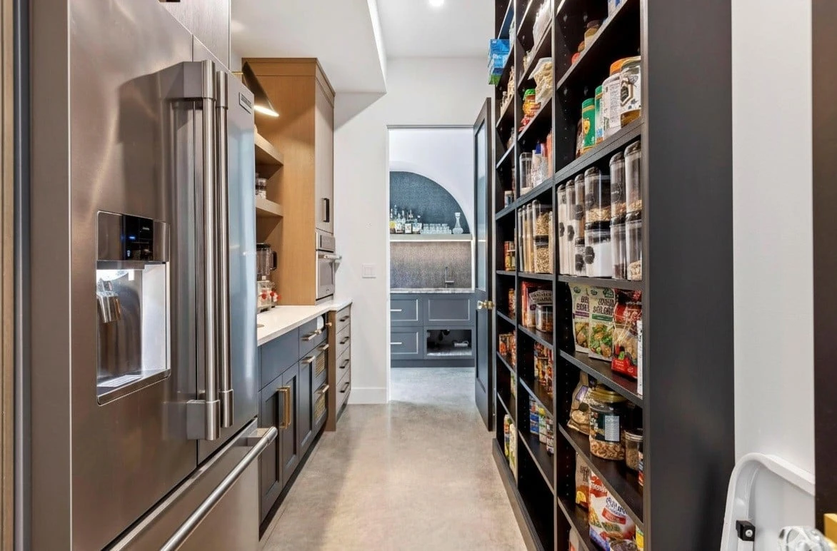 Stellar Craft Cabinetry Inc. modern kitchen pantry with custom cabinetry, stainless refrigerator, and organized shelves