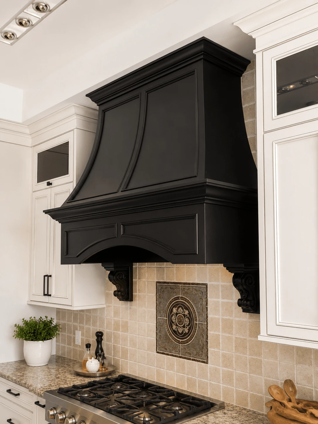 Stellar Craft Cabinetry Inc. black custom range hood over tiled kitchen backsplash