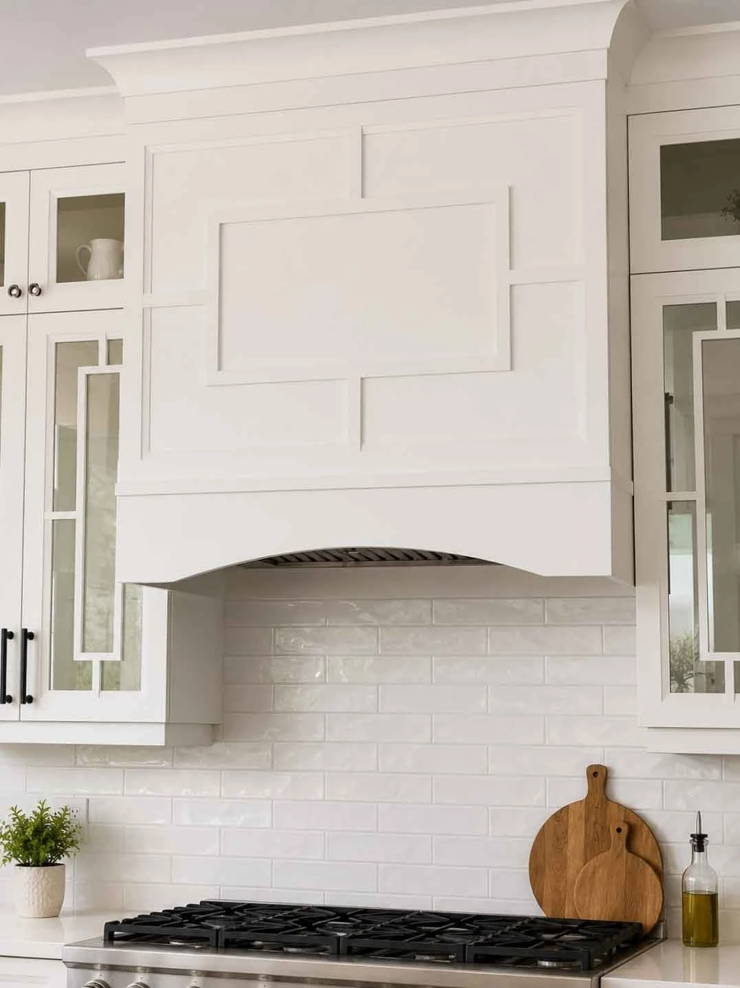 Stellar Craft Cabinetry Inc. custom white kitchen cabinets with range hood and backsplash