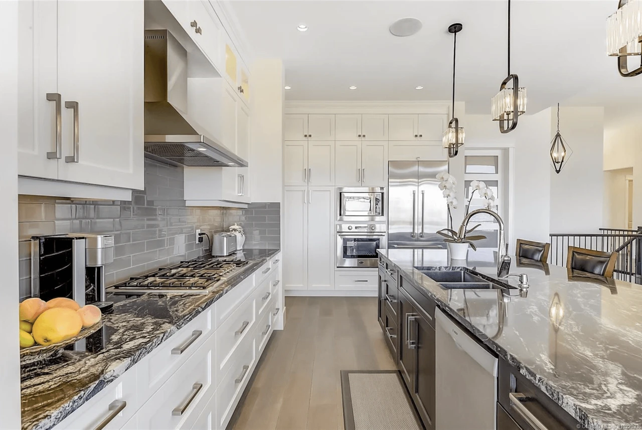 Stellar Craft Cabinetry Inc. modern white kitchen with custom cabinetry, gray subway tile backsplash, and stainless appliances