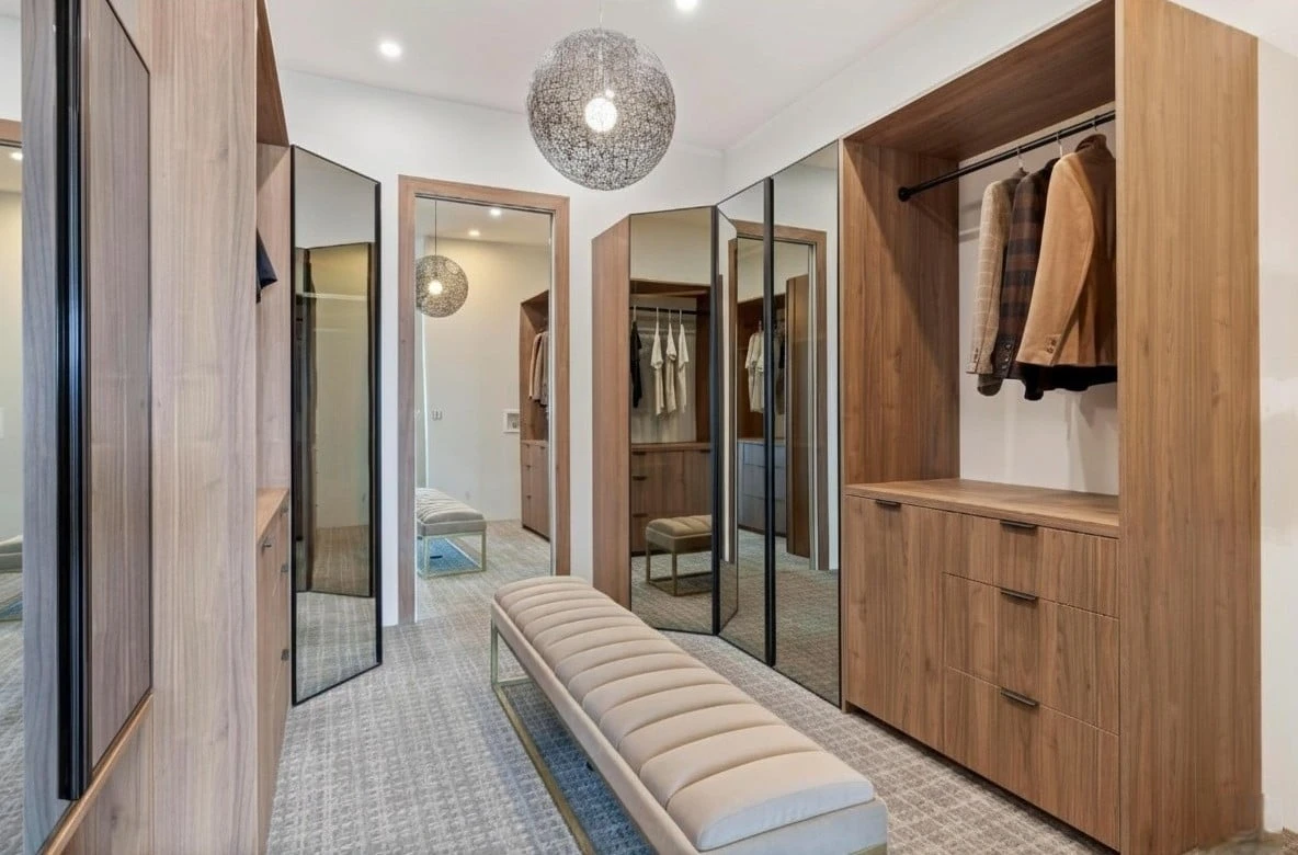 Stellar Craft Cabinetry Inc. custom modern walk-in closet with wood cabinetry, mirrored doors, and built-in bench